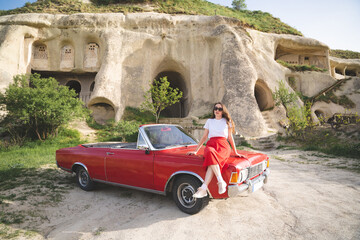 beautiful happy girl in a skirt posing near a retro car in the mountains of cappadocia