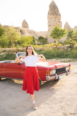 beautiful happy girl in a skirt posing near a retro car in the mountains of cappadocia