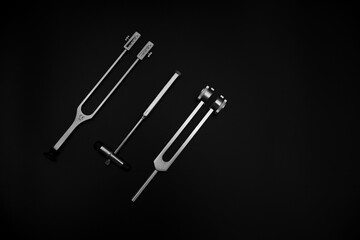 tuning fork C 128 on a black background with gradation and otorhinoscope and neurological hammer