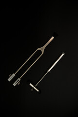 tuning fork C 128 on a black background with gradation and otorhinoscope and neurological hammer