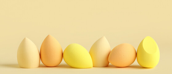Many makeup sponges on yellow background