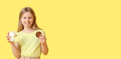 Happy little girl with milk and tasty cookie on yellow background with space for text