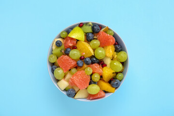 Bowl with fresh fruit salad on blue background
