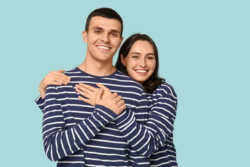 Cheerful young couple hugging on blue background
