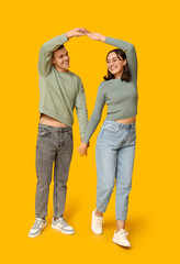 Obraz premium Happy young couple dancing together on yellow background
