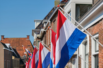 Dutch flags in a typical dutch street on Koningsdag under a blue sky. Koningsdag is a national holiday in the Kingdom of the Netherlands.	