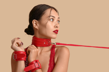 Sexy young woman in red handcuffs and collar on color background. Erotic concept
