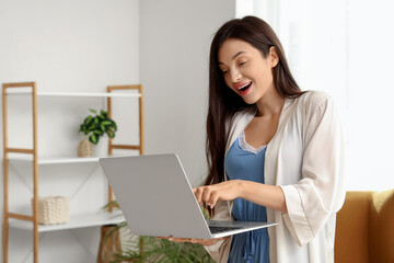 Young woman in pajamas working with laptop at home