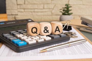 Q and A written on wooden cubes. electronic devices, and paper, wood table from above