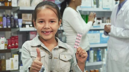 Little girl holding medicine and giving a thumbs up