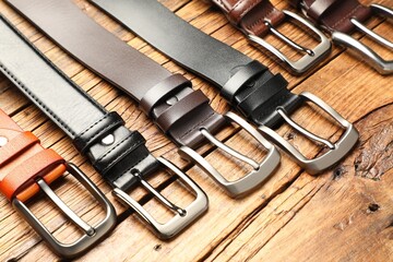 Many different leather belts on wooden table, above view