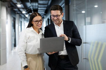 Positive businesspeople collaborating on laptop computer, brainstorming over company startup, motivated colleagues looking at laptop screen discussing business ideas together