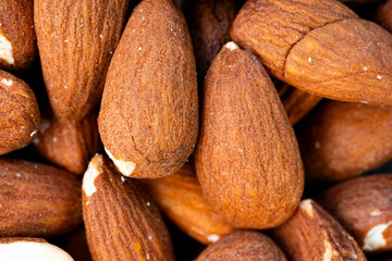 Close-up macro image of whole roasted almonds with visible texture and natural brown color,...