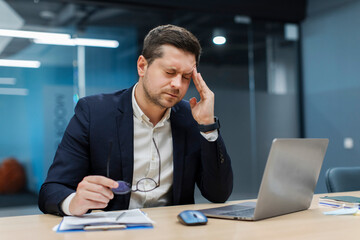 Overtired businessman took off glasses and touching temples, suffering from migraine and headache,...