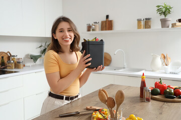 Young woman with compost bin in kitchen
