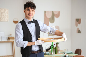 Male waiter holding tray with glasses in restaurant