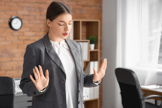 Young businesswoman trying to calm down while having panic attack in office