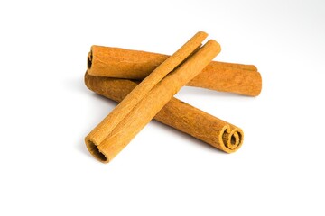Assorted dried cinnamon bark pieces on white, focusing on their natural curves and coarse surfaces.