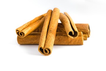 Close-up of broken cinnamon bark pieces on a white surface, emphasizing their rustic texture and warm hues.