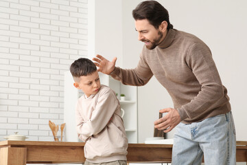Fototapeta premium Young father and his little son squabbling in kitchen