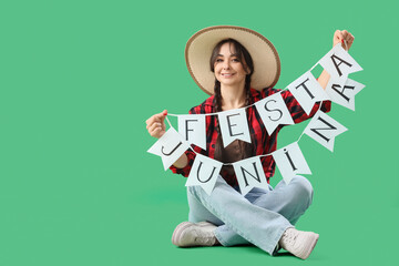 Young happy woman in straw hat holding bunting with text FESTA JUNINA on green background