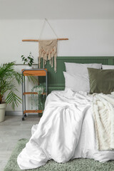 Interior of bedroom with bed and green plants