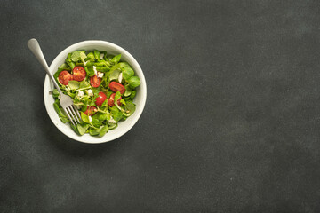 Colorful tomato salad with pine nuts on black background.