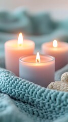Three Burning Candles On Soft Blue Knitted Blanket Photo