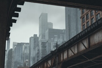 Obraz premium Cityscape viewed from under a bridge on an overcast day. Tall buildings dominate the skyline.