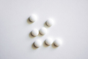 Set of seven round white tablets arranged on clean white surface