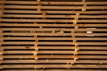 Horizontal stack of timber boards with strong shadows and light texture