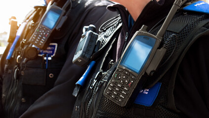 Police officers – Close-up of station police officers stab proof vest uniform worn by a couple of department cops at the scene of an incident. Officers enforce the law and protect the public.