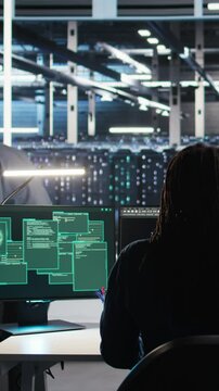 Vertical video Cybersecurity team in data center responds to security breach, trying to prevent unauthorized access. Workers rushing to secure servers and protect sensitive information during