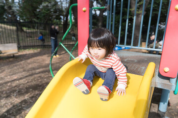 公園の滑り台で遊ぶ女の子