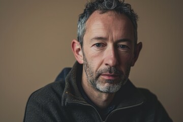 Portrait of a handsome mature man with grey hair and beard, wearing a black hoodie.
