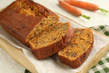 Homemade carrot cake with nuts and vegetables on white textured table, closeup