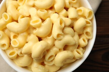 Delicious macaroni and cheese on wooden table, top view