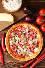 Tasty pizza with smoked sausages and ingredients on wooden table, flat lay