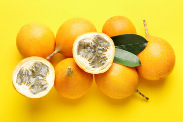 Ripe passion fruits and leaves on yellow background, flat lay