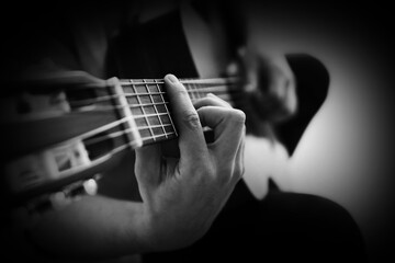 Man playing guitar on dark background, closeup. Black and white effect