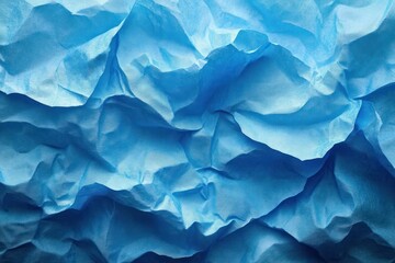 Obraz premium Close-up of wrinkled, textured blue paper creating abstract shapes and depth with varying shades of blue and soft shadows