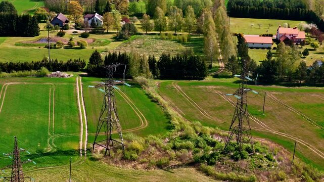 Rural field near village area with separated property lines outlined by electricity pylons and tree rows in spring