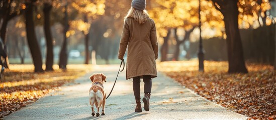 A woman walks her dog down a tree lined path