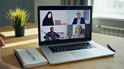 Close-up of laptop with interface of video call software interface showing four diverse colleagues talking in an online meeting, home office setting - Powered by Adobe