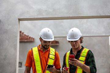 Two male Caucasian engineers are having conversation on quality inspection using a check list in a construction site. Supervisor is working with his coworker in a concrete floor making factory outdoor