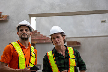Two male Caucasian engineers are having conversation on quality inspection using a check list in a construction site. Supervisor is working with his coworker in a concrete floor making factory outdoor