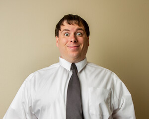 A man wearing a white shirt and a black tie is smiling and looking at the camera