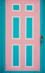 Puerta vintage de madera con diseño geométrico en tonos pastel rosa y turquesa