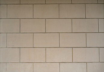Pared de bloques rectangulares de concreto beige con textura suave y diseño simétrico – fondo arquitectónico minimalista
