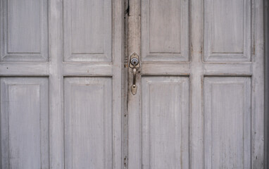 Fototapeta premium Puerta antigua de madera gris con cerradura vintage en fachada colonial - foto de stock 